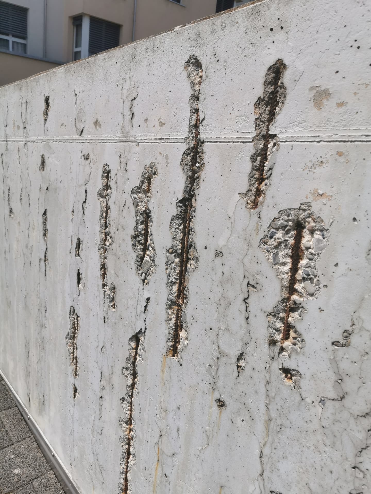 Betonwand mit Abplatzungen und rostender Bewehrung